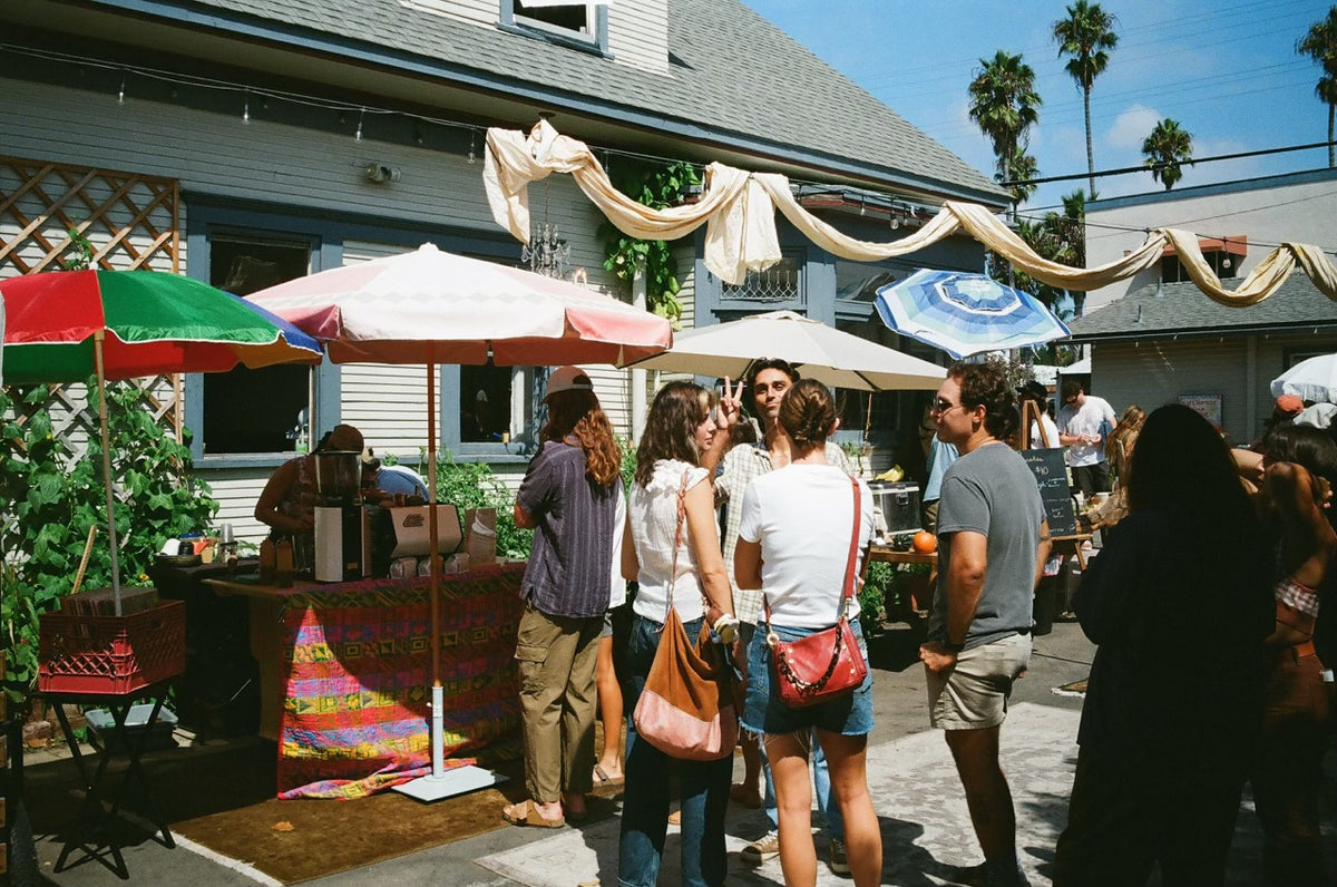 Outdoor gathering at the Dear Tomorrow craftsman house with market umbrellas